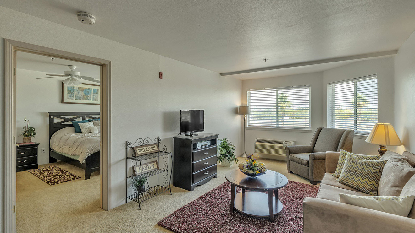 Peoria, AZ carpeted senior apartment with windows in living room and ceiling fan in bedroom.